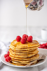 Sweet homemade pancakes with raspberries and blueberries on white plate.