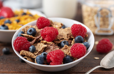 Healthy breakfast of granola chips with blueberries and strawberries on dark desk.
