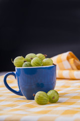 Cup with cherry-cherry-plums. Blue ceramic coffeecup overfilled with green cherry-cherry-plums.