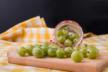 Many cherry-cherry-plums poured out of a jar. Wooden board for cooking.