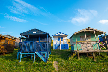 Colourful wooden beach huts facing the ocean at Whitstable coast,  Kent district England.