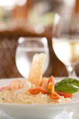 Risotto with shrimp, tomato and basil and glass in the back