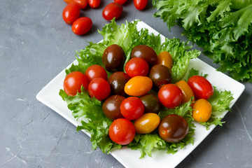 Fresh cherry tomatoes and lettuce on a white plate.