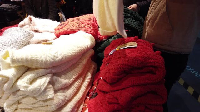 The buyer chooses a sweater in the mall.
