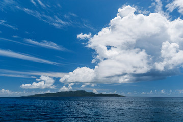 View from the sea on one of the Seychelles Islands under a white cloud