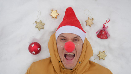 Guy in the image of Santa is lying on the snow around him Christmas toys and shows different...