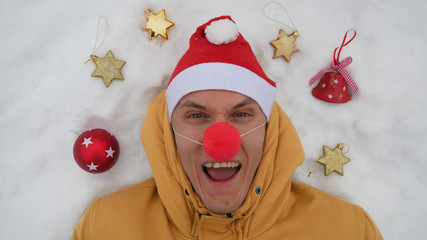 Guy in the image of Santa is lying on the snow around him Christmas toys and shows different...