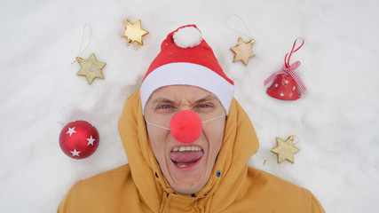 Guy in the image of Santa is lying on the snow around him Christmas toys and shows different...