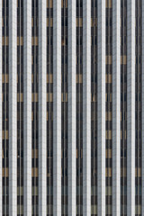 Vertical view of a grid of multiple floors of office windows in a modern concrete, glass and steel skyscraper with white columns
