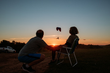 people watching a paragliding at sunset