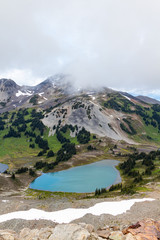 Snowy mountains with a lake at the bottom and cloudy sky