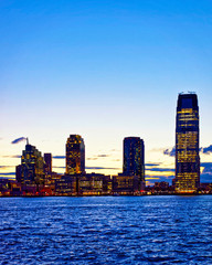 Night Jersey City, New Jersey and Hudson River. View from Manhattan, New York of USA. Skyline and cityscape with skyscrapers at United States of America, NYC, US. Road and American architecture.