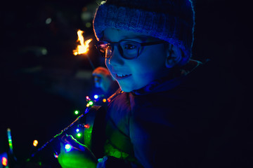 Little boy with a sparkler  bengal fire on a christmas night background