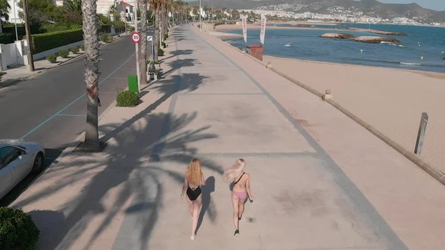 Girls in swimsuits are walking along the promenade. Sitges. Spain.