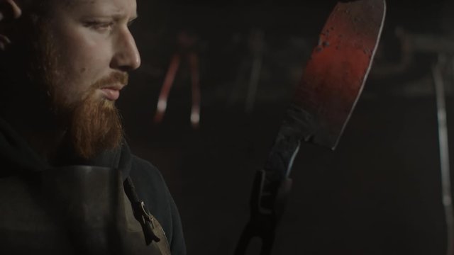 Portrait of a blacksmith perfecting his blade in a dark interior of his metal workshop. 