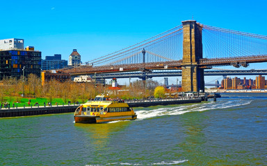 Ferry at Brooklyn band Manhattan bridge across East River, New York, USA. It is among the oldest in...