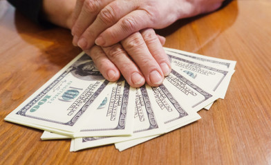Hands of an old woman with dollars on the table