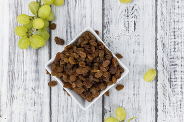 Portion of healthy Raisins on an old wooden table (selective focus; close-up shot)