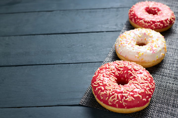 Colorful glazed donuts on dark wooden background.