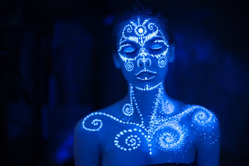 Body art on the body and hand of a girl glowing in the ultraviolet light.