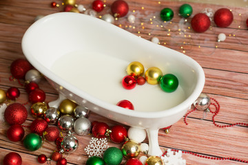 Naklejka na ściany i meble background texture. children's bath with Christmas toys balls. Christmas decor in a milk bath