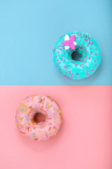 Two donuts on pastel pink and blue background. Minimalism creative food composition. Flat lay style