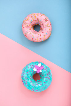 Naklejka Two donuts on pastel pink and blue background. Minimalism creative food composition. Flat lay style