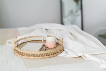 Fototapeta na wymiar Coffee in pink mug, notebook, and glasses on tray sitting on bed, coffee in bed, pink bedroom decor