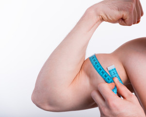 Close up photo of fitness man measuring biceps with tape