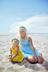 Happy family relaxing by the sea. Happy family resting at beach in summer.Young mother and her adorable little daughter on beach vacation. Concept of summer,childhood and leisure