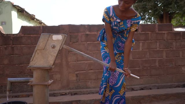 Close Up View Of An African Girl Pumping Water At The Community Well 