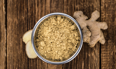 Some Ginger Powder on a vintage wooden table (selective focus; close-up shot)
