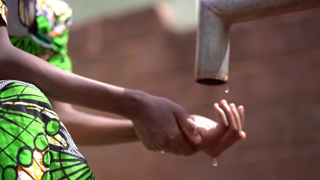 African Girl Collecting Water Drops At A Drying Out Village Pump Station