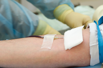 male hand with a needle in a vein in the hospital blood transfusion unit. blood and bone marrow...