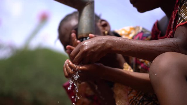 Two Little African Girls Refreshing Themselves At The Village Water Pump