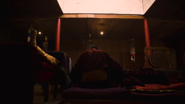 monk praying from behind in a dark