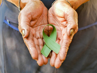 Hands old woman holding nature ribbon with coconut leave. Breast world cancer day.