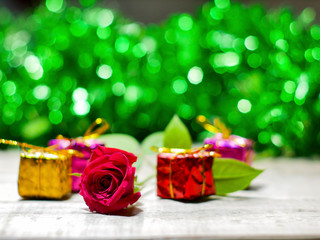 Red rose and gift box on green bokeh background. Valentine's day greeting card.