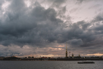 Dramatic sky above Peter and Paul fortress in Saint Petersburg. The boat is floating on the Neva river. Copy space. The most tourist city in Russia. Tourism and vacation concept.