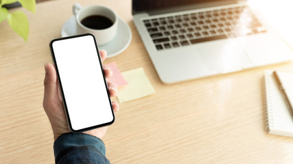 Mockup image blank white screen cell phone.man hand holding texting using mobile on desk at office.background empty space for advertise text.people contact marketing business,technology 