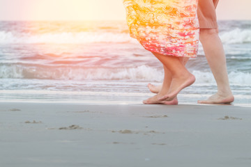 Human legs walking through the sunny morning light at the beach. Couple keep a walk at beach.