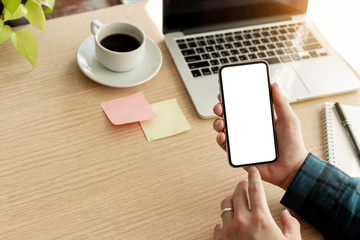 Mockup image blank white screen cell phone.man hand holding texting using mobile on desk at office.background empty space for advertise text.people contact marketing business,technology 