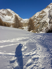 Winter hiking in Aosta Valley, Cogne, Italy. Walking in the Grauson valley. My shadow on the snow.