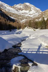 Winter hiking in Aosta Valley, Cogne, Italy. Crossing a bridge  in the Grauson valley.
