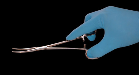 hand in a blue glove holds a medical instrument isolated on a blue background, surgeons save lives