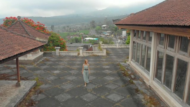 Aerial shot of a woman tourist visiting the abandoned and mysterious hotel in Bedugul. Indonesia, Bali Island. Bali Travel Concept