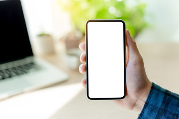 Mockup image blank white screen cell phone.man hand holding texting using mobile on desk at coffee shop.background empty space for advertise text.people contact marketing business,technology 