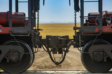 Close up of train coupler connecting two wagons of a Canadian freight or cargo train. Yellow fields...