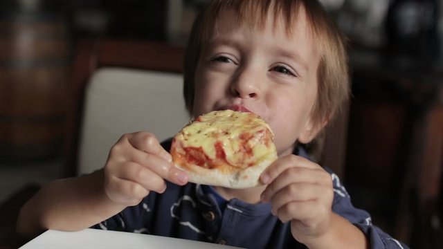Close up of little cute boy eating pizza. Neutral colors for collor correction.