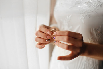 beautiful bride holds a wedding ring with a diamond in her hands